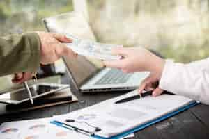 Free photo businessman giving money to his partner while making contract