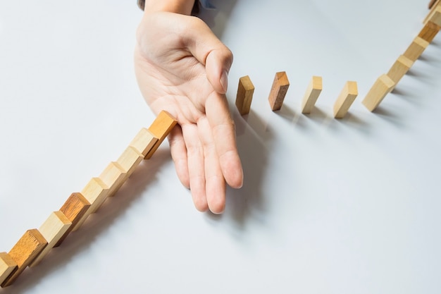 businessman hand stop dominoes continuous toppled or risk with copyspace