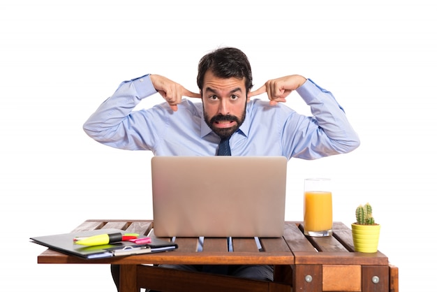 Free photo businessman in his office covering his ears