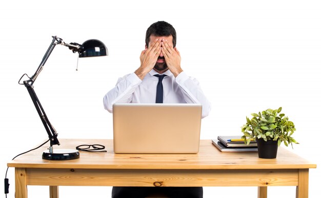 Businessman in his office covering his eyes