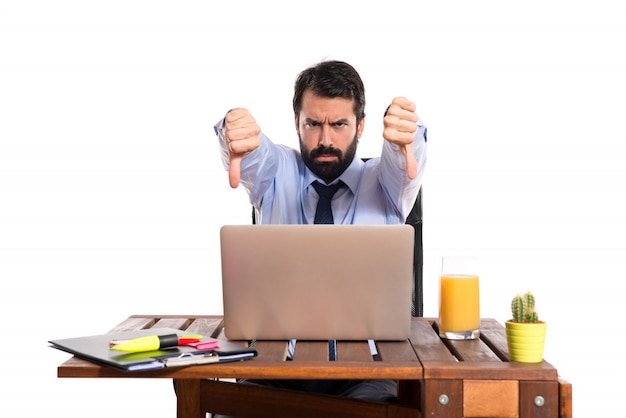 Free photo businessman in his office  doing a bad signal