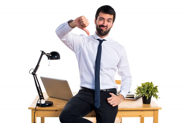 Businessman in his office doing bad signal