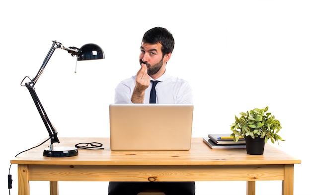 Businessman in his office doing a money gesture