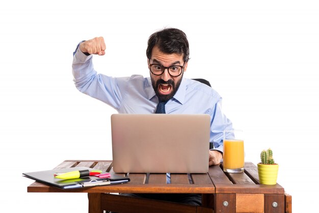 Businessman in his office giving punch over white background