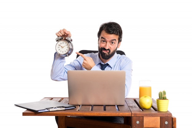 Free photo businessman in his office holding a clock