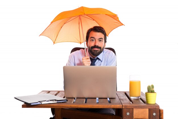 Businessman in his office holding an umbrella