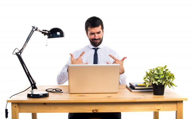 Businessman in his office making horn gesture