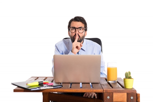 Businessman in his office making silence gesture