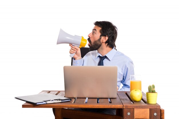 Businessman in his office shouting by megaphone