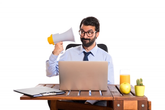 Free photo businessman in his office shouting by megaphone