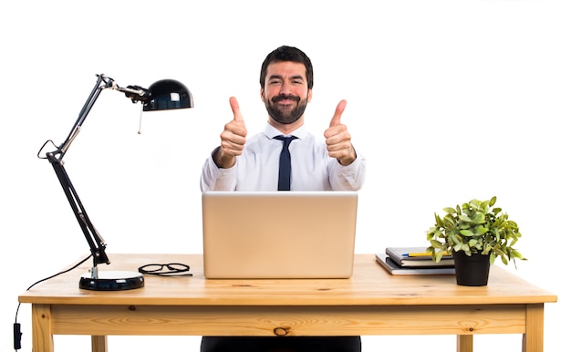 Businessman in his office with thumb up