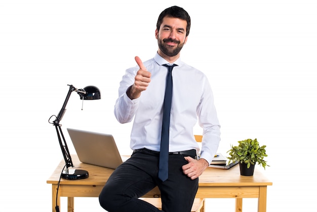 Businessman in his office with thumb up
