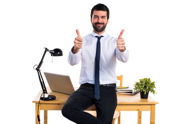 Businessman in his office with thumb up