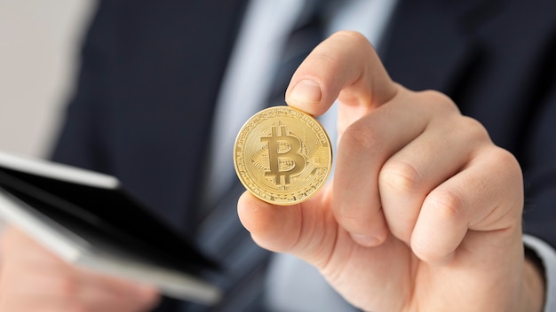 Free Photo businessman holding a bitcoin close-up