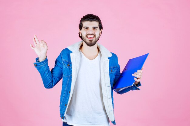 Free photo a businessman holding a blue folder and feeling satisfied