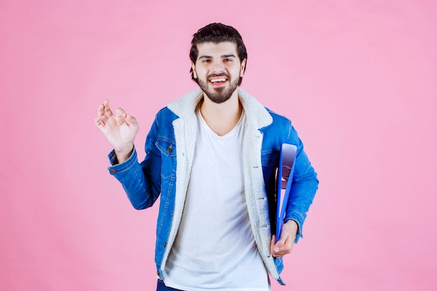 A businessman holding a blue folder and feeling satisfied