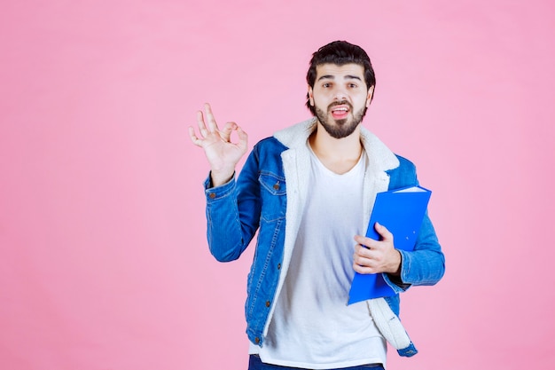 A businessman holding a blue folder and feeling satisfied