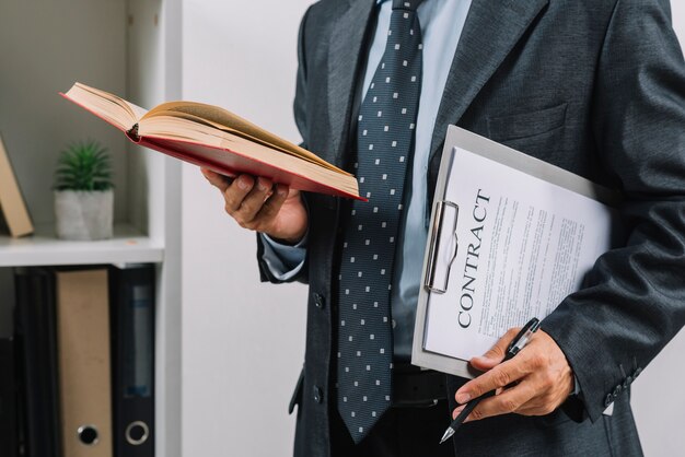 Businessman holding book and clipboard with contract