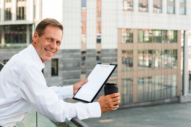 Businessman holding clipboard looking at camera