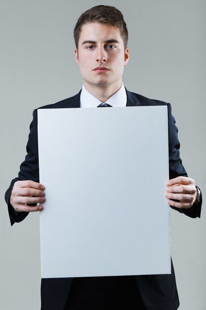 Businessman holding empty white placard showing copy space.