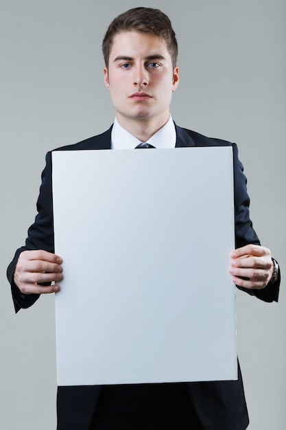 Businessman holding empty white placard showing copy space.