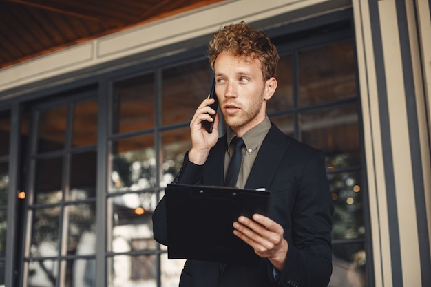 Businessman holding a folder in his hands. Handsome confident businessman wearing suit standing.