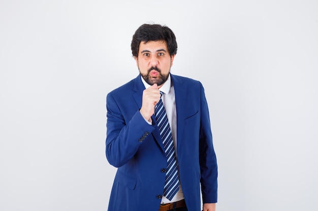 Businessman holding hand as microphone in formal suit and looking serious. front view.