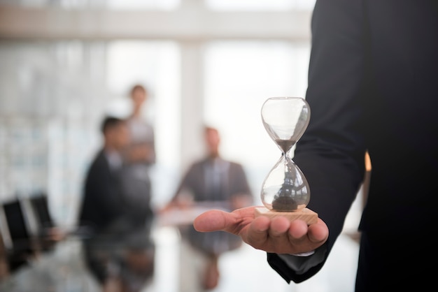 時間ガラスを持っている実業家は、時間通りになることの重要性を示しています