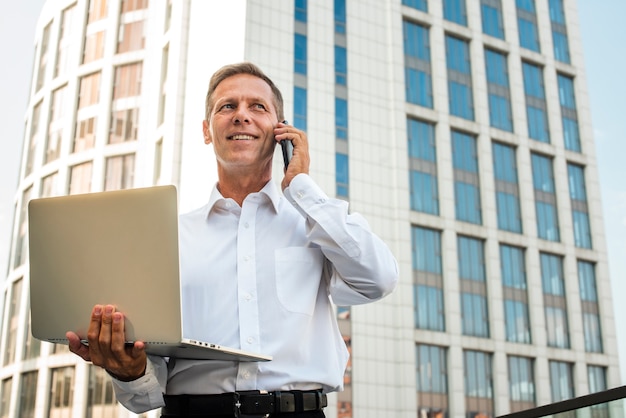 Businessman holding laptop talking on the phone