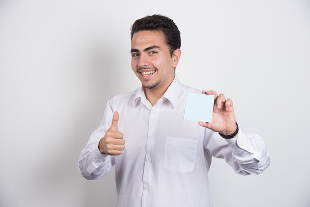 Businessman holding memo pads and showing thumbs up on white background.