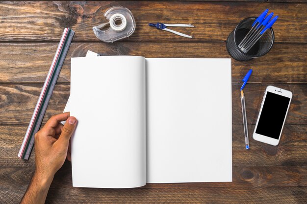 Businessman holding white paper surrounded with stationeries and cellphone