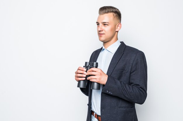 Businessman is looking through a pair of binoculars isolated on white wall