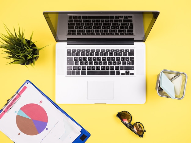 Free photo businessman laptop on yellow desk top view concep, headphones, pot of grass ,sunglasses