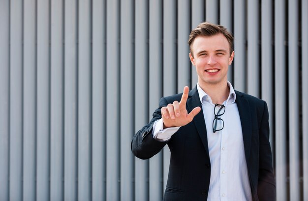 Businessman looking at camera with two fingers up