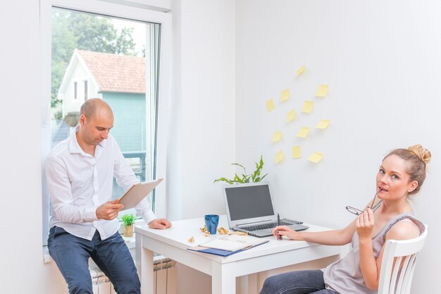 Businessman looking at digital tablet near his partner sitting on chair