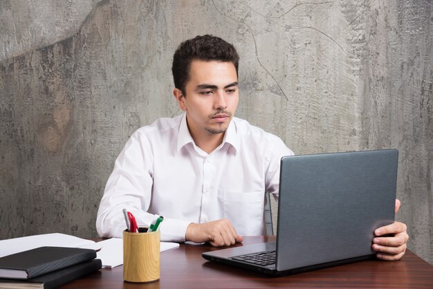 Businessman looking into laptop and sitting at the desk. High quality photo