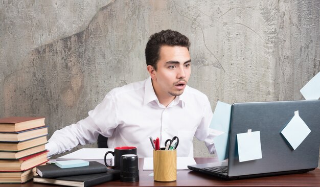 Free photo businessman looking laptop with shocked expression at the office desk.