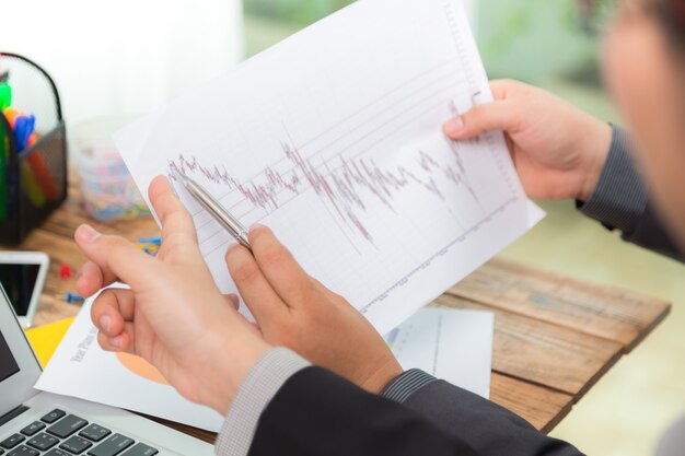 Businessman looking at a paper with graphs