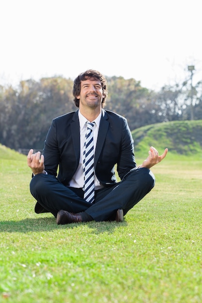 Businessman meditating in lotus position outdoors