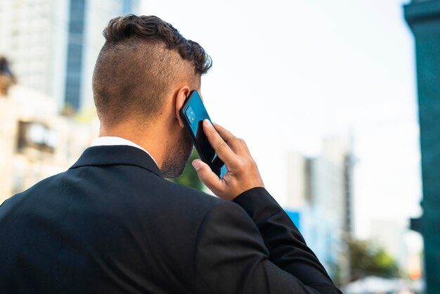 Бизнесмен на открытом воздухе разговаривает по телефону со спины