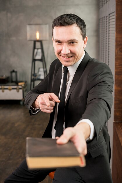 Businessman pointing at camera and recommending book
