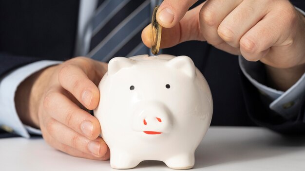 Businessman putting a coin in a piggy bank