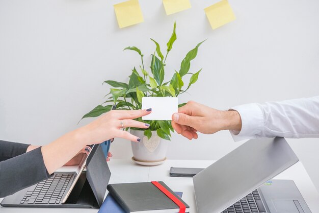 Businessman's hand giving card to his partner in office