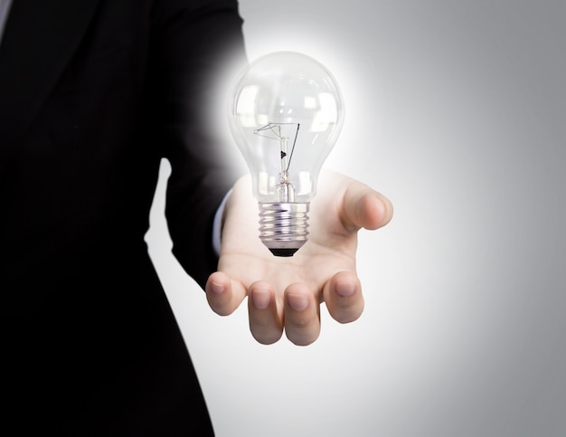 Free photo businessman's hand next to a light bulb