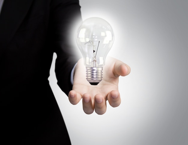 Businessman's hand next to a light bulb