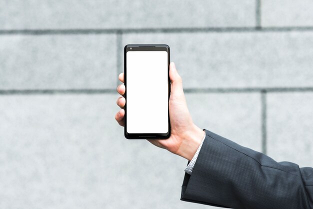 Businessman's hand showing blank mobile screen against blurred backdrop