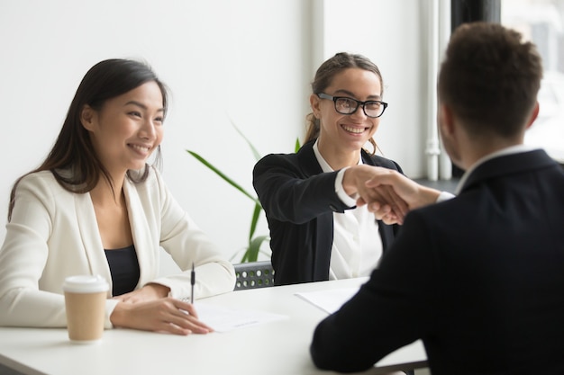 Businessman shaking hand of female coworker during company meeting