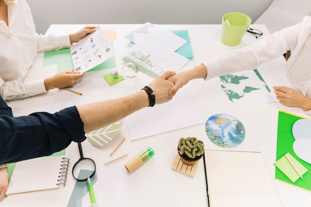 Free photo businessman shaking hands with his partner over desk