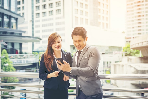 Businessman showing mobile phone to colleague outside.