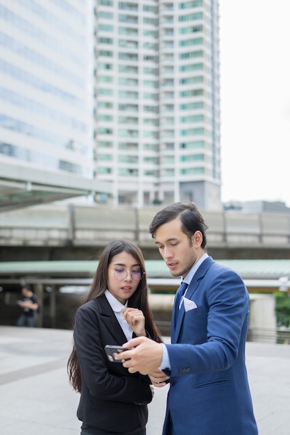 外の同僚に携帯電話を示す実業家。